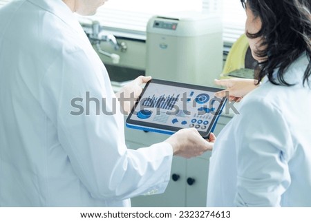 Group of researchers looking at tablet data in the lab. Research and Development. Royalty-Free Stock Photo #2323274613