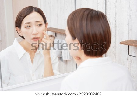 Asian middle aged woman having skin trouble Royalty-Free Stock Photo #2323302409
