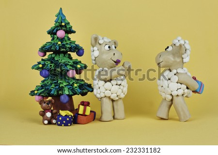Clay sheep is presenting gift to another near the Christmas tree