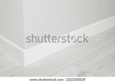 White plinth with connector on laminated floor near wall indoors, closeup Royalty-Free Stock Photo #2323330529