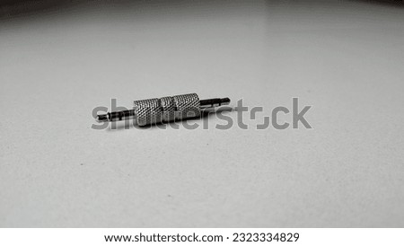 3.5 mm jack adapter of a silver color, such adapters are used for music and media transfer. 