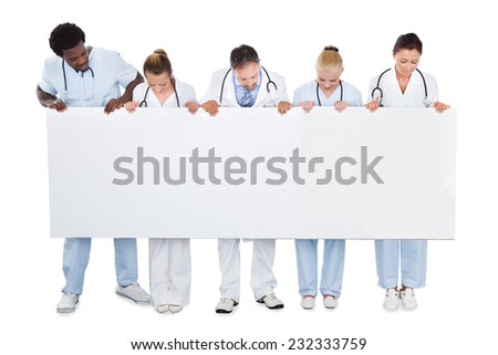 Full length of multiethnic medical team looking at blank billboard over white background