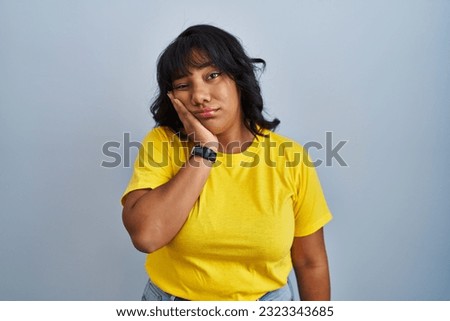 Hispanic woman standing over blue background thinking looking tired and bored with depression problems with crossed arms. 