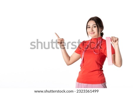 Front view of a smiing young girl in redorange blouse holding accessory on white background Royalty-Free Stock Photo #2323361499