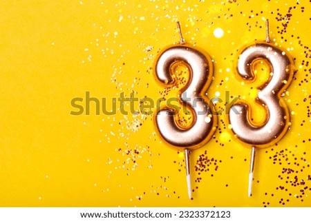 33 years celebration. Greeting banner. Gold candles in the form of number twenty eight on yellow background with confetti.