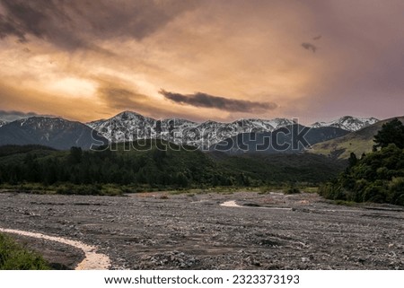 Beautiful New Zealand sunset over dried river and snowy mountains