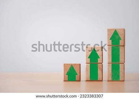 Green increasing up arrow print screen on wooden cube block ,It is symbol of business investment growth concept.