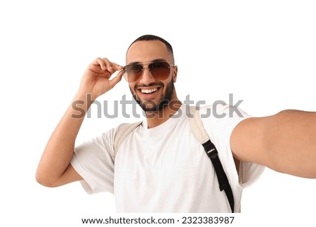 Smiling young man in sunglasses taking selfie on white background