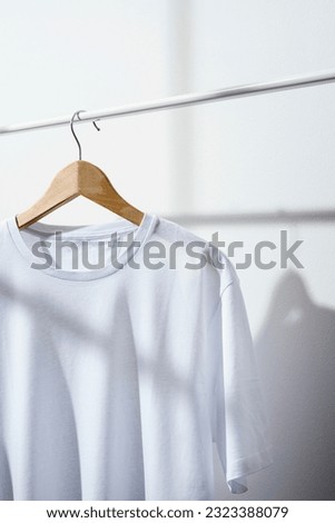 Blank white t-shirt mockup, template on wooden hanger displayed on a white clothes rack
