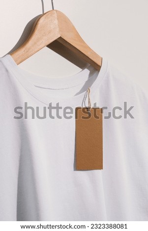 White t-shirt with blank brown price tag mockup, template on wooden hanger