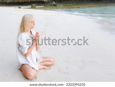 Side view of blonde woman sitting yoga asana at seashore beach