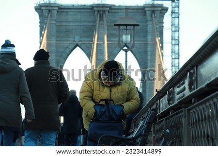 Man checking his backpack on busy Brooklyn Bridge, New York 