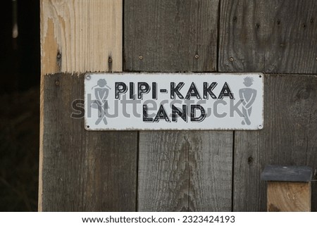 A restroom sign hung on a wooden door with a white background
