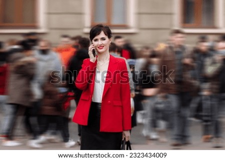 Young confident businesswoman in formalwear, red jacket is talking on smartphone while walking on city street. Telecommunication and mobile network for business concept. Female Business Style.