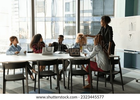 Skilled young female african american business trainer giving professional consultation to motivated group business people, sharing knowledge or developing corporate growth strategy in modern office. Royalty-Free Stock Photo #2323445577