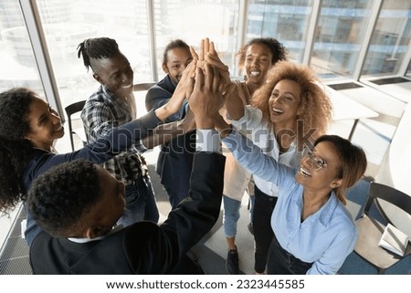 Above top view happy friendly young african american diverse colleagues joining hands in air, celebrating shared corporate success, effective teamwork, raising working spirit, teambuilding concept. Royalty-Free Stock Photo #2323445585
