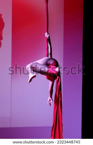 Acrobatic aerial dance dancer on red fabrics.