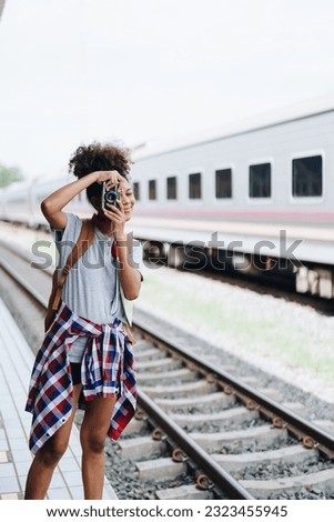Asian teenage girl african american traveling using a camera take a photo to capture memories while waiting for a train at the station