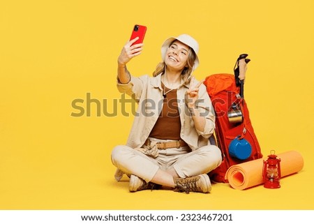 Full body young woman carry bag with stuff mat sit do selfie shot mobile cell phone show v-sign isolated on plain yellow background. Tourist walk on spare time. Hiking trek rest travel trip concept