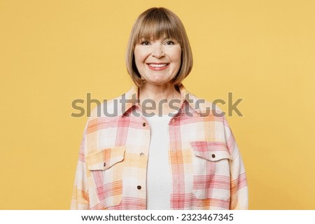 Elderly smiling cheerful fun cool satisfied positive blonde caucasian woman 50s years old she wear casual clothes looking camera isolated on plain yellow background studio portrait. Lifestyle concept