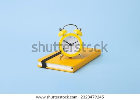 Front view of yellow alarm clock staying on notebook.Back to school concept.