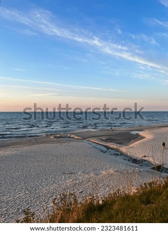 Seascape, view to the sandy beach at the sunset time, people walking on the beach