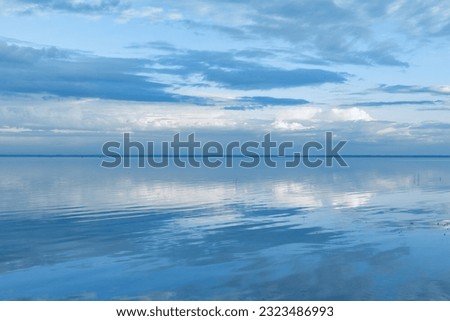 Beautiful white blue clouds over lake, symmetric sky background, cloudscape on lake Ik, Russia. Nature abstract, cloudy sky reflected on water, calm windless weather, natural environment, skyline Royalty-Free Stock Photo #2323486993