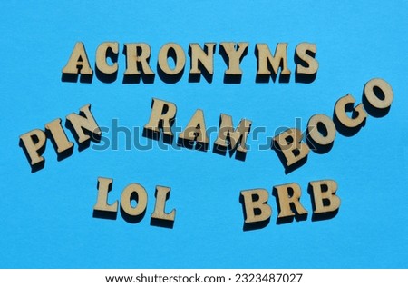 Acronyms, including PIN, LOL, BRB, BOGO and RAM in wooden alphabet letters isolated on blue background Royalty-Free Stock Photo #2323487027
