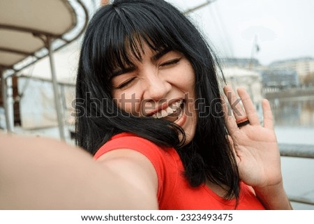 Selfie portrait of young latin woman of venezuelan ethnicity dressed in red, with black hair, smiling happy outdoors, tourist in the city of Buenos Aires, lifestyle concept, close-up portrait.