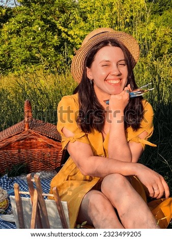 Painter's paradise: woman in a yellow dress and hat creates art during a picnic.