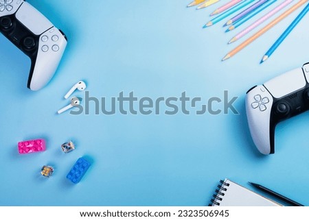 Blue children's table with Next Generation white game controller, colored pencils, earphone and dice. Child accessories. Kids. Space for text. and dice. Child accessories. Kids. Space for text.