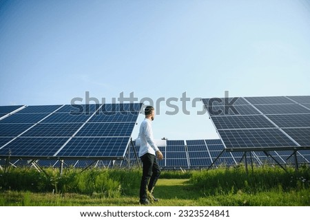 Solar power plant. Man standing near solar panels. Renewable energy Royalty-Free Stock Photo #2323524841