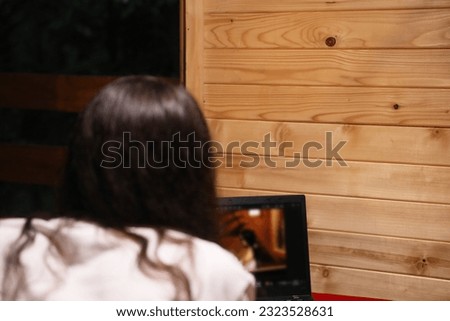 Young happy woman working on laptop in bed. Attractive female studying online using web service on laptop. Back view over the shoulder. On-line education concept