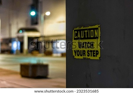 A sign with 'caution watch your step' words on wall