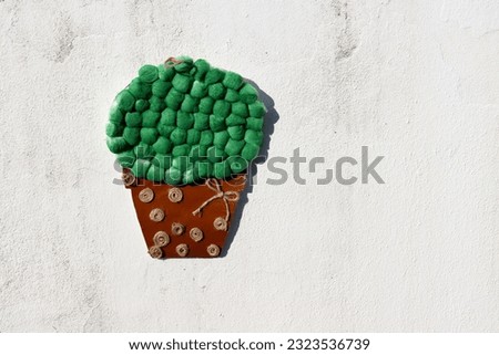 Brown pot with green flowers made of cotton and paper. Children's application.