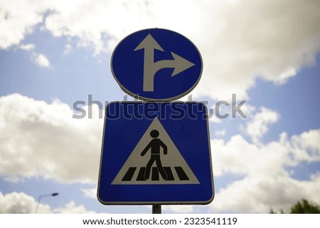 A low angle shot of a pedestrian sign against a blue sky