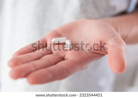 White capsules with collagen in male hand. Nutritional supplement, medicine, drug for joints protection, skin care, health care. Health support and treatment concept. Royalty-Free Stock Photo #2323544451