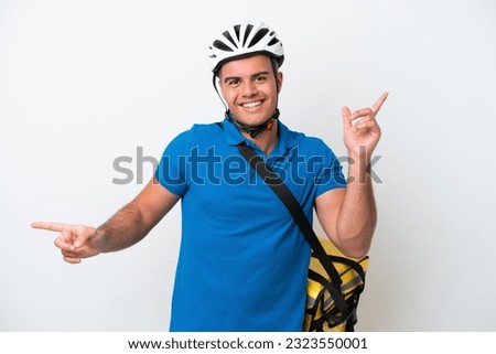 Young caucasian man with thermal backpack isolated on white background pointing finger to the laterals and happy