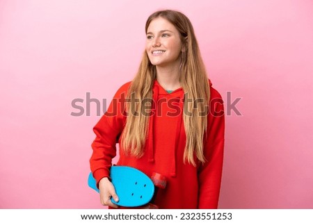 Young blonde woman isolated on pink background with a skate