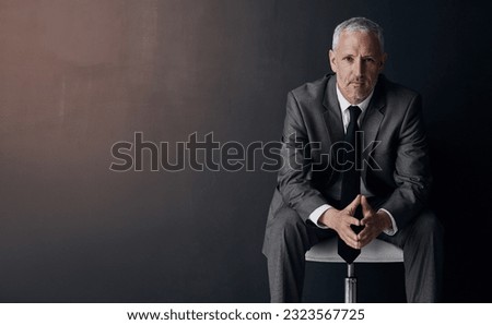 Mock up, chair and serious portrait of lawyer, attorney or businessman with confidence on dark background in studio space. Boss, ceo or business owner, proud senior executive director at law firm. Royalty-Free Stock Photo #2323567725