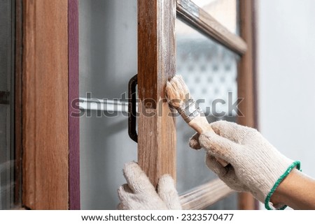 Worker use brush apply wood preserver after sandling the old surface of wooden window Royalty-Free Stock Photo #2323570477