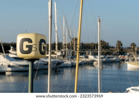 A G sign on a port wharf against boats docked in the harbor on blur background