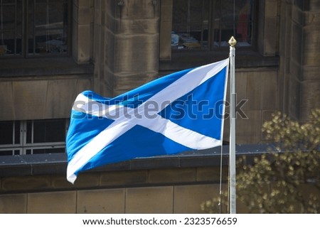 The flag of Scotland in blue and white colors waving on a pole on a street