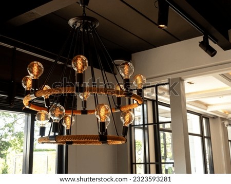 Modern chandelier in living room near glass window, loft style, vintage ceiling light or light bulbs hanging with from wooden ceiling, indoor, interior loft style building. Retro lighting decoration. Royalty-Free Stock Photo #2323593281