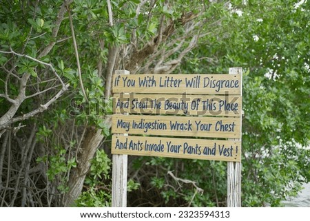 A rustic wooden sign post warning against littering in the Florida Keys