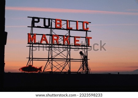 A neon public market sign at Pike Place Market and Elliott bay during the sunset