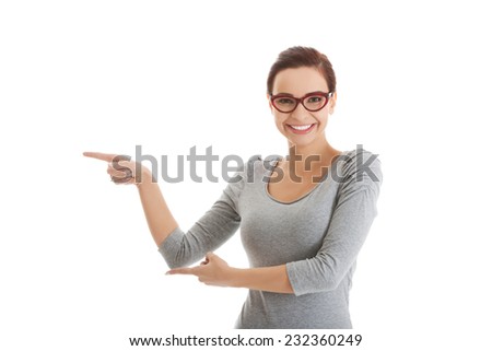 Young woman pointing towards blank space.