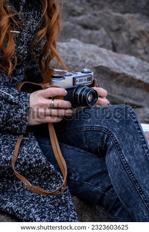 Girl sitting on a rock with a retro camera