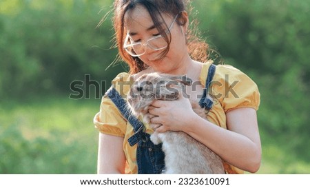 Beautiful asian woman with rabbit. happy girl holding cute fluffy easter bunny.Friendship with Easter Bunny. Spring photo with beautiful young girl with her Bunny. Girl is holding a cute little rabbit