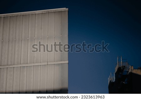 Modern office building. Corner of house in industrial architectural style. Aluminum facade of a building. Metal, stainless steel exterior wall cladding. Geometric lines in architecture. Dark key photo